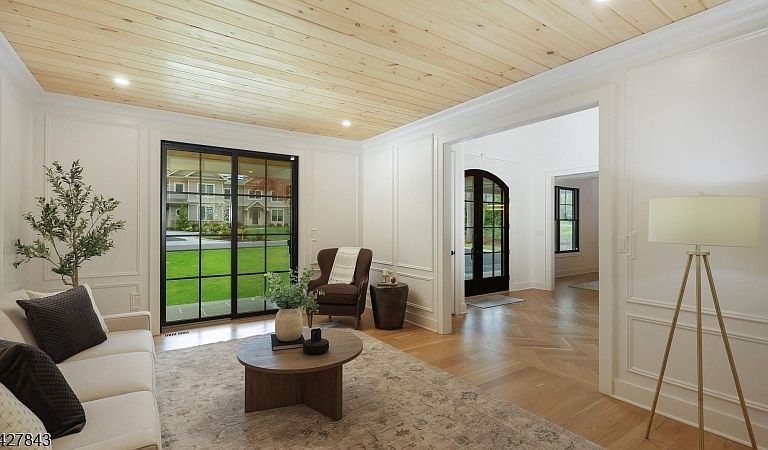 A second view of the living room showing the broader proportions and the herringbone hardwood flowing through to the foyer.